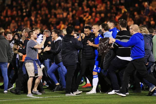 Luke Norris of Colchester United is surrounded by fans after they invade the pitch following Colchester United victory in the penalty shoot during the Carabao Cup Third Round match between Colchester United and Tottenham Hotspur
