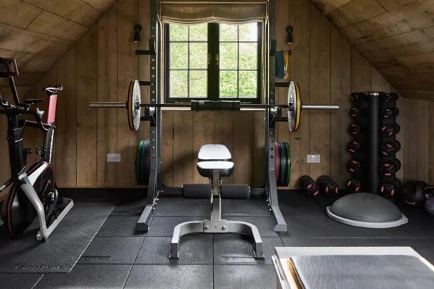 A ground-floor service corridor leads to a double garage, and a separate staircase leads to a home gym above