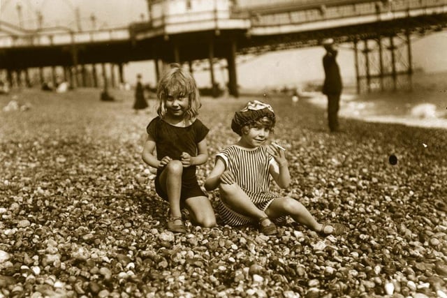 Two young girls on Brighton beach are about to have a cigarette, circa 1910: