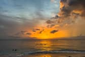 TOPSHOT - People swim in the ocean as the sun sets in the parish of Saint James, Barbados, on June 22, 2024. (Photo by CHANDAN KHANNA / AFP) (Photo by CHANDAN KHANNA/AFP via Getty Images)