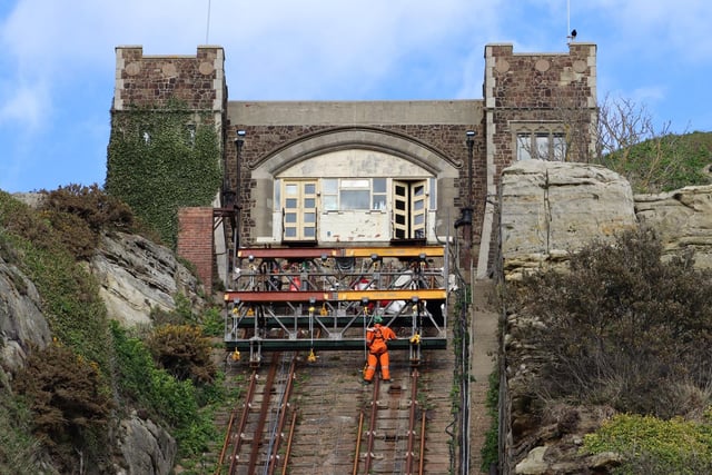 Workers using special safety harnesses on the near vertical cliff railway