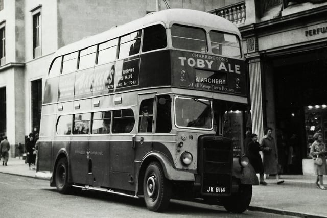 The Eastbourne Corporation bus is outside Boots and this photo shows the original frontage of the store which included a colonnade with display cabinets as can be seen in the photo. In the background is the rebuilt Barclays Bank, the original building was destroyed in World War II. Although not very clear the advert on the side of the bus was for Barkers, a department store that used to occupy the T J Hughes site, they were taken over by Army & Navy Stores more popularly know as A & N.