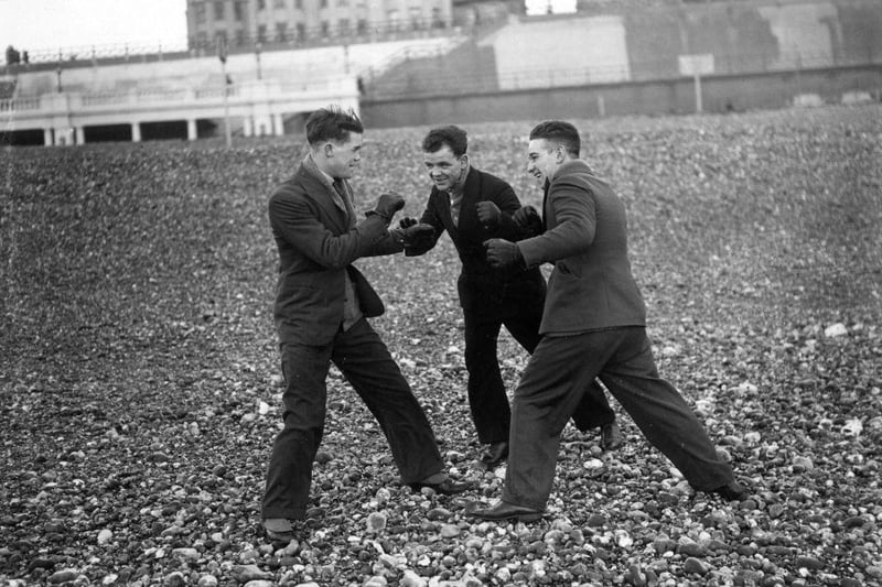 English boxer Teddy Baldock sparring with fellow boxers Jim Briley and Sid Raiteri on the beach at Brighton on 10th January 1930.