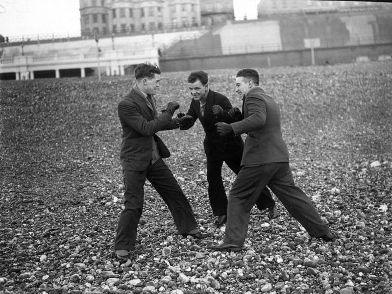 English boxer Teddy Baldock sparring with fellow boxers Jim Briley and Sid Raiteri on the beach at Brighton on 10th January 1930.