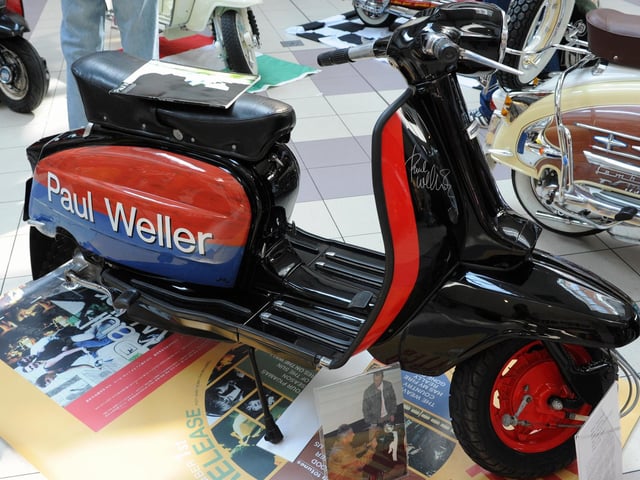 A scooter signed by musician Paul Weller, with a photo of the moment he penned his name