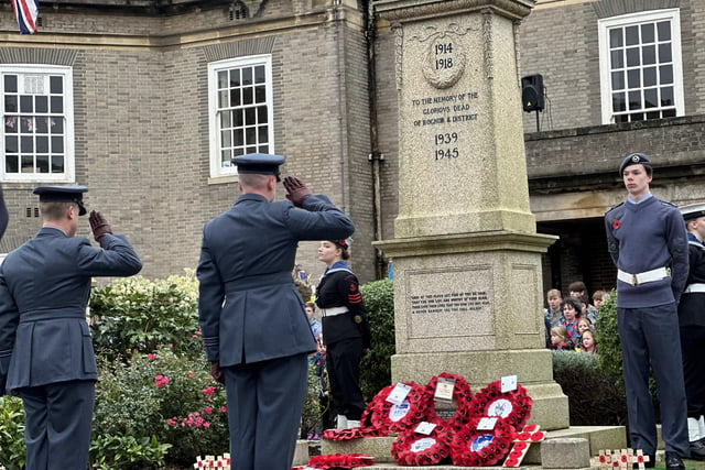 Armed forces staff salute after laying a wreath.