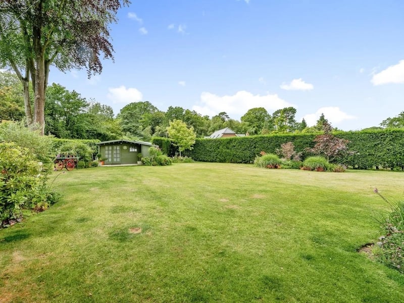 The landscaped rear garden features a patio and decked area leading to large lawned garden