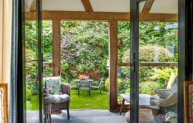 French doors lead into an  oak framed veranda with slate tiled flooring and galleried ceiling looking over the landscaped garden.