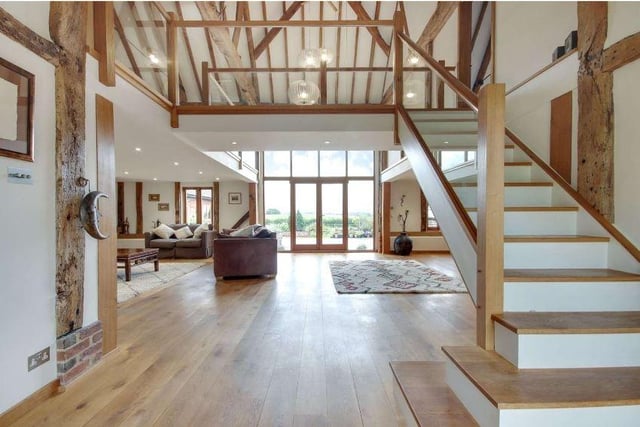The original barn forms the principal vaulted reception room, which has distinct sections including an entrance hall with adjoining cloakroom, a sitting room with a Jetmaster fire, and a separate area for dining