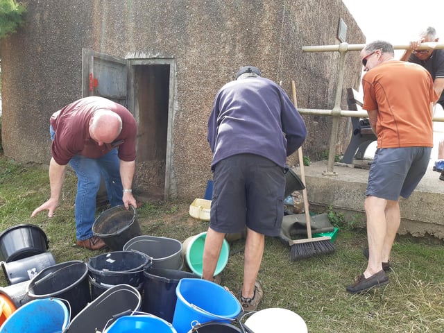 A bucket chain of volunteers from Ferring History Group and Ferring Conservation Group, including Worthing West MP Sir Peter Bottomley, form a bucket chain to bail out nine inches of water from the Ferring pillbox