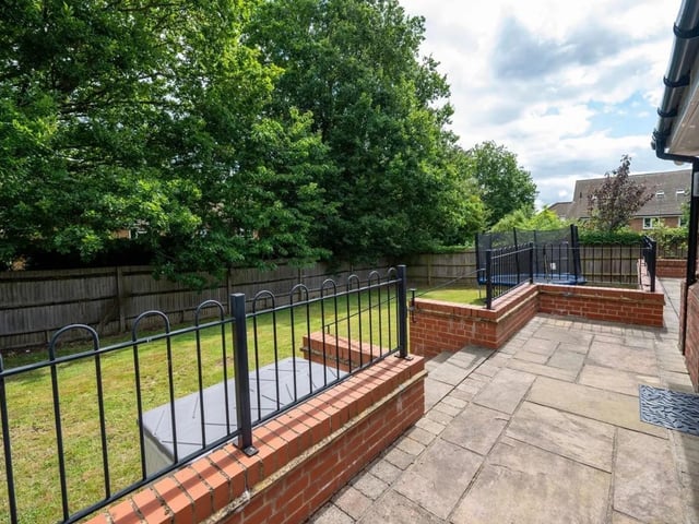The private garden at the rear has a raised terrace area and a large lawn