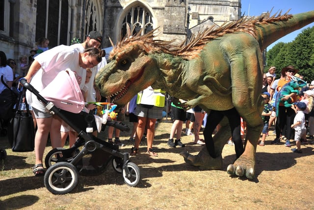 T-Rex greets a baby at Chichester Cathedral. Pic S Robards SR2208131
