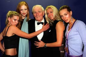 The world famous 'Q', Desmond Llewelyn, surrounded by a group of Bond Girls in 1999