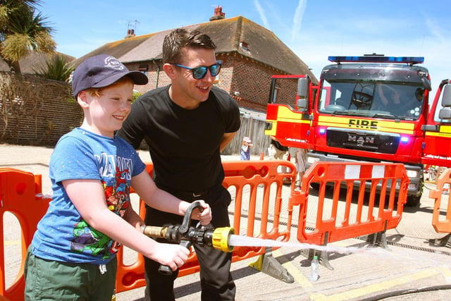 Eight-year-old James Morgan has a go with the hose, with the help of firefighter James West