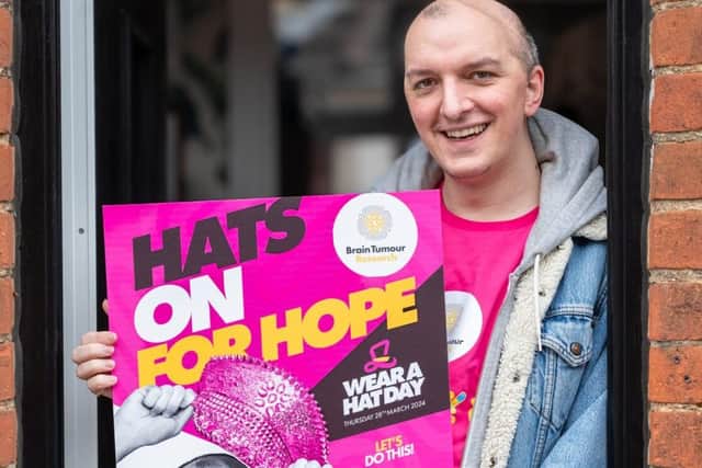 Eddie Adams with the Wear A Hat Day poster he features on