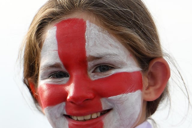 A young England fan in face paint looks on.
