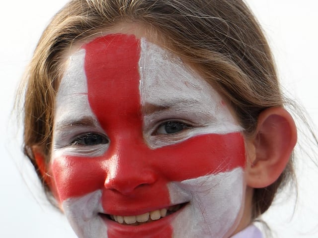 A young England fan in face paint looks on.