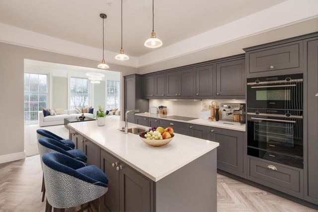The kitchen has an array of built-in appliances, a feature island and an elegant grey herringbone floor