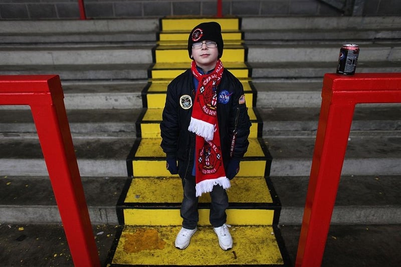 A young fan of Crawley Town poses in Broadfield Stadium before boarding the coach to Manchester.
