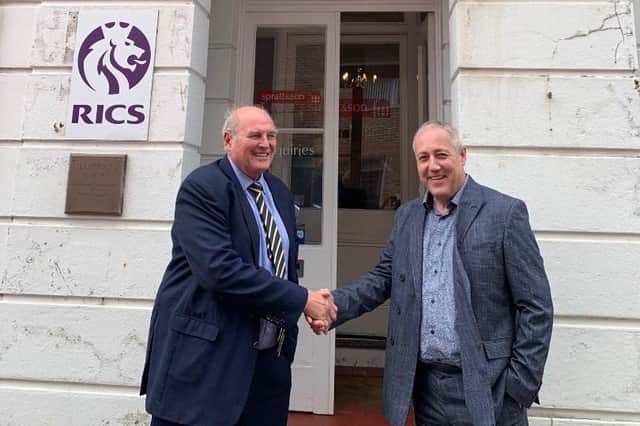 Chris Spratt and Peter Hewett shake hands in front of CG Spratt & Sons following business merger 