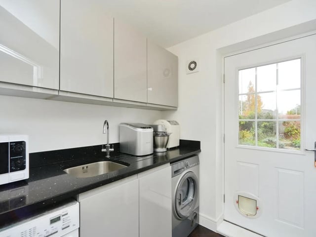 A separate utility space has a single drainer sink, an integrated washing machine, space for a dryer, and a single door leading to the garden