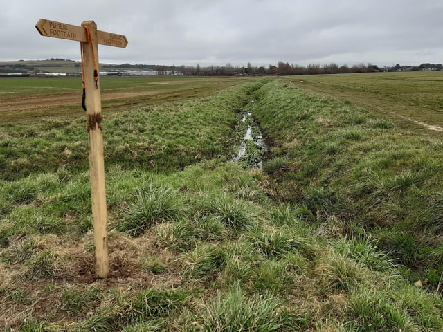 You will soon come to more water and a footpath sign