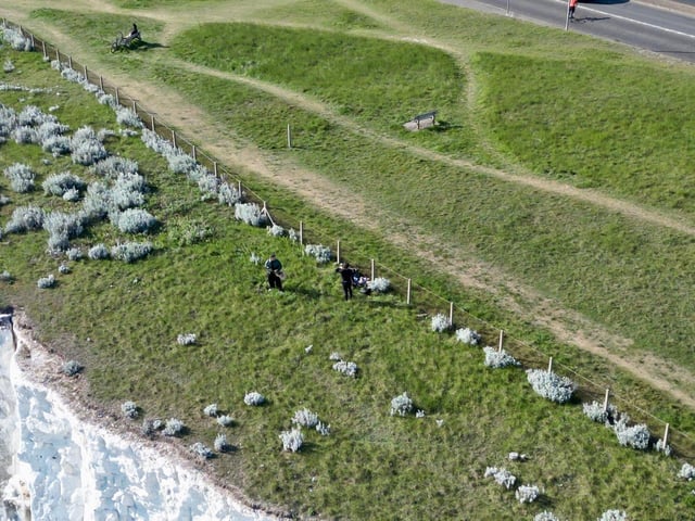 People climbing over the barrier near the cliff edge in Saltdean on Thursday, May 7. Photo: Eddie Mitchell