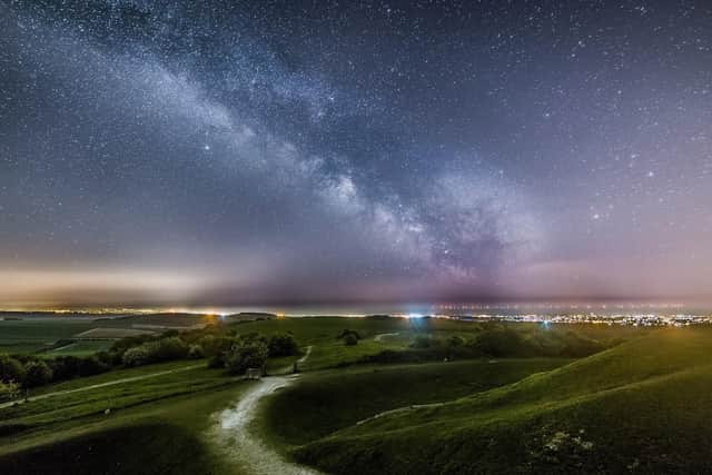 The milkyway above the lights of Worthing and Brighton from Cissbury Ring with the lights of the Rampion Wind farm in the background