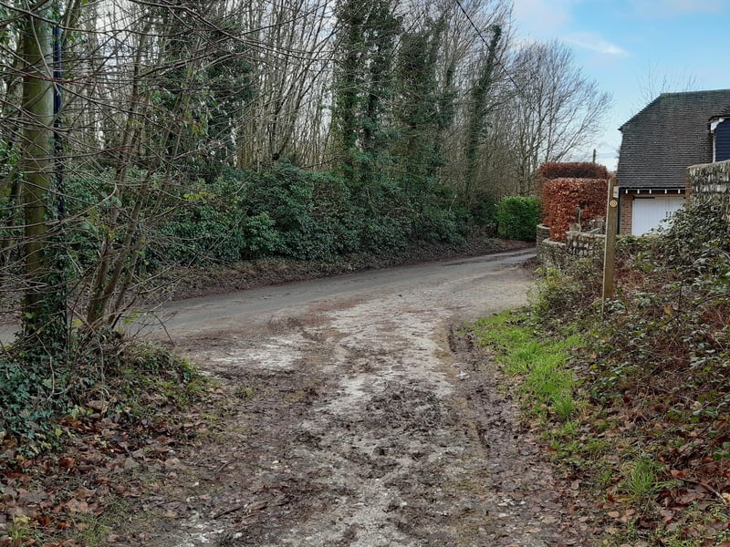 As you join the road, turn right to continue down the hill.