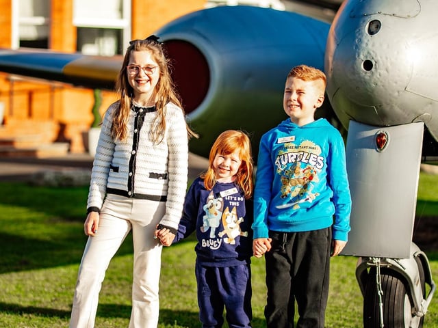 Daisy visiting Weald Hall Care Home in Thornwood, Epping, amazed by the Gloster Meteor aircraft proudly displayed at the front of the home, pictured here with RJ and Alya, children from the programme, sharing a moment of wonder and discovery.