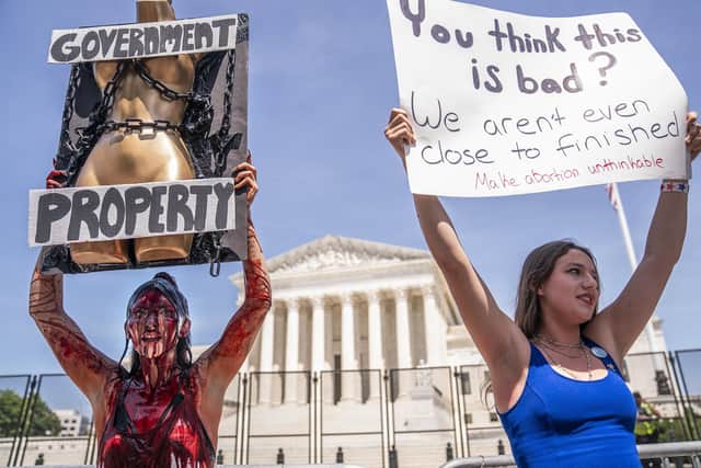 Abortion-rights supporter Sam Scarcello (L) and anti-abortion activist Elianna Geertgens hold competing signs in front of the Supreme Court while covered in fake blood on July 4, 2022 in Washington, DC (Photo by Nathan Howard/Getty Images)