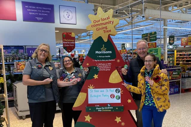 Morrisons community champion Alison Whitburn shows Charlie and Grace Sims from St Peter and St Paul's Pantry in Rustington how the Giving Tree works