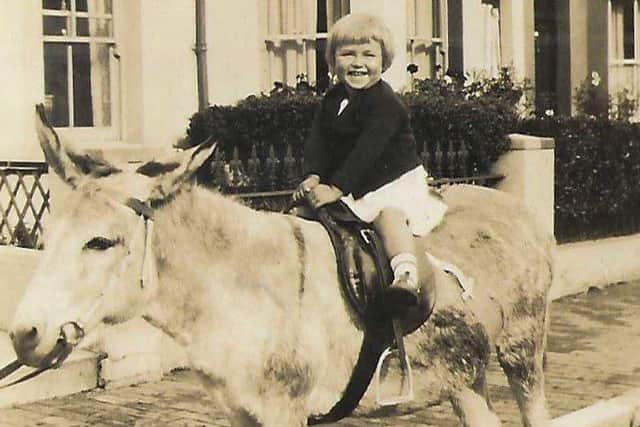 A young rider on a saddled donkey on Eastbourne seafront.