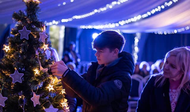 A guest at Tree of Light hangs a star of dedication on the tree 