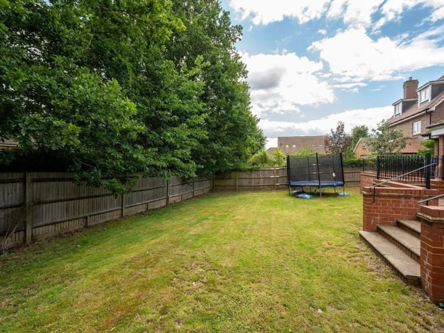 The private garden at the rear has a raised terrace area and a large lawn