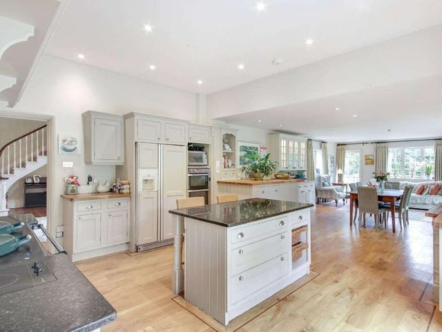 The kitchen, breakfast and family room forms the hub of the home for day to day family life, with plenty of space for a central breakfast table and for sofas around a gas log-effect fire in one corner. The kitchen area is fitted with a range of hand painted bespoke cabinetry with wood block worktops and a marble-topped island, together with a two-oven Aga and various appliances