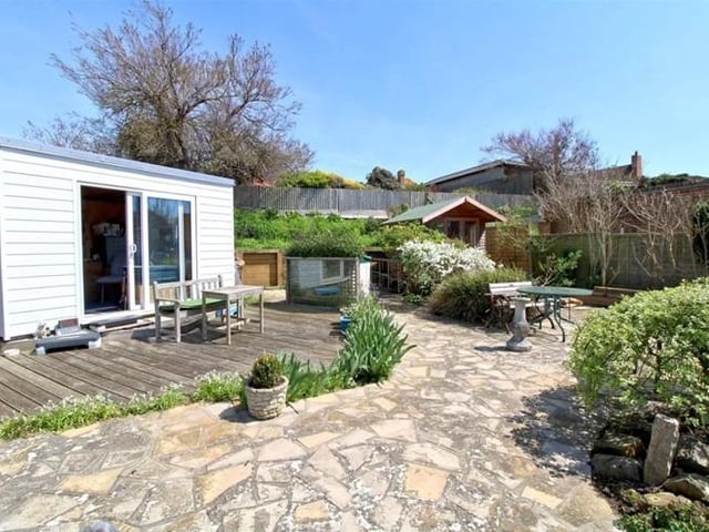 In the garden the decked area leads to an artificial lawn and steps down to swimming pool. The steps lead up to a patio area with mature planting, with decking next to a timber studio, a rockery with a pond and a bank with wildflower planting.