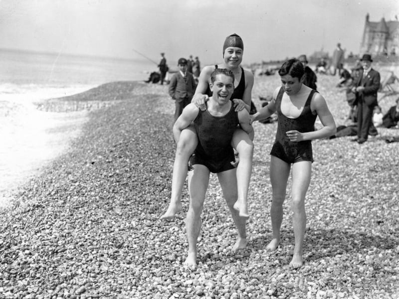 16th April 1927: A male bather carries a female friend over the shingle on the beach at Brighton.