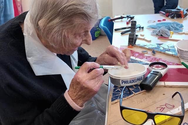 Blind veteran Irene (96) working on the Union Flag with raised relief of Kind Charles III.