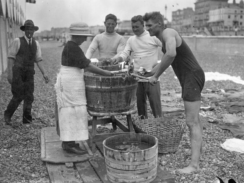British Heavyweight Champion Phil Scott gives a hand at the mangle on Brighton beach on 20th August 1925. .