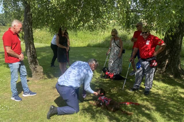 MP Steve Barclay kneels to pet a dog at Service Dogs UK