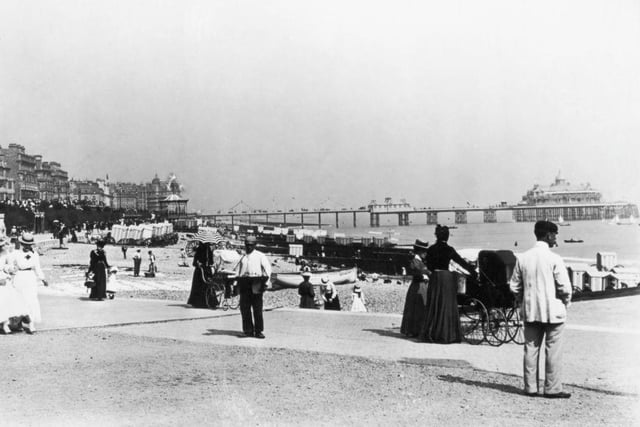 Holidaymakers on the sea front at Eastbourne, with Eastbourne pier in the background, circa 1895.