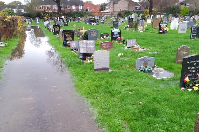 The flooded pathway and graves at Horsham's Hills Cemetery