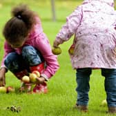 Children collecting apples in the garden at Bateman's, East Sussex.