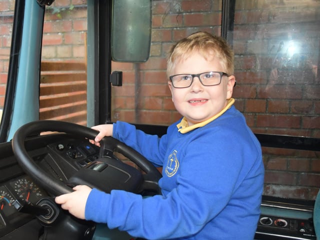 An enthusiastic pupil takes the wheel of the new bus