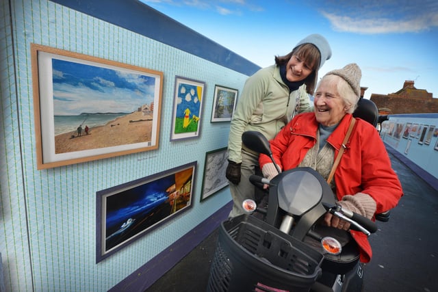 Footbridge Gallery 2.0 at Bexhill railway station.
Rita Taylor (right) looking at her Beach View artwork with daughter Miranda Taylor.