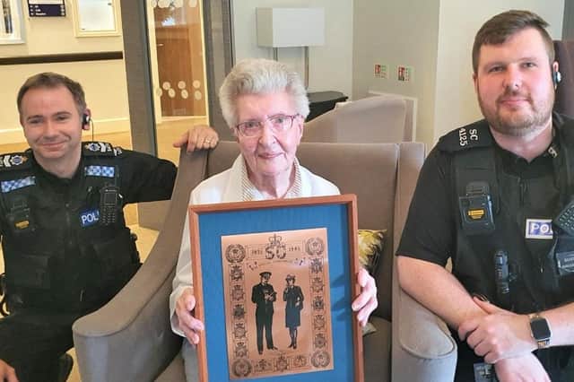 Beryl Saunders holding her donated artwork, photographed with Operational Head of the Special Constabulary, Ryan Seibel and Special Sergeant, Paul Nash. Photo: Sussex Police