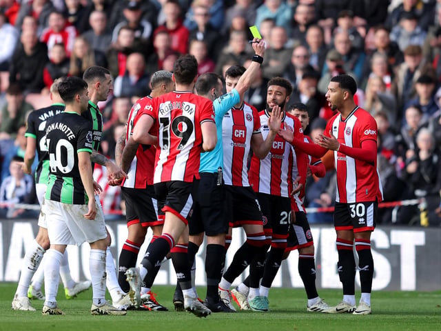 SHEFFIELD, ENGLAND - FEBRUARY 18: Referee Stuart Attwell shows a yellow card to Mason Holgate of Sheffield United, which is later upgraded to a red card after a VAR review during the Premier League match between Sheffield United and Brighton & Hove Albion at Bramall Lane on February 18, 2024 in Sheffield, England. (Photo by Matt McNulty/Getty Images)