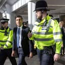 Prime Minister Rishi Sunak speaks with police officers as they walk in the corridors of the Swan Walk shopping centre during a visit in Horsham, West Sussex, on April 10. (Photo by RICHARD POHLE/POOL/AFP via Getty Images)