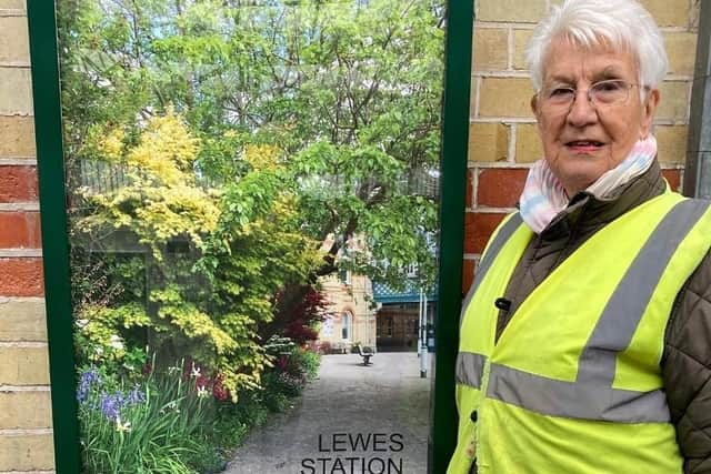 Lewes Pots and Plants lead volunteer Mary Sautter with a newly installed poster displaying the station gardens